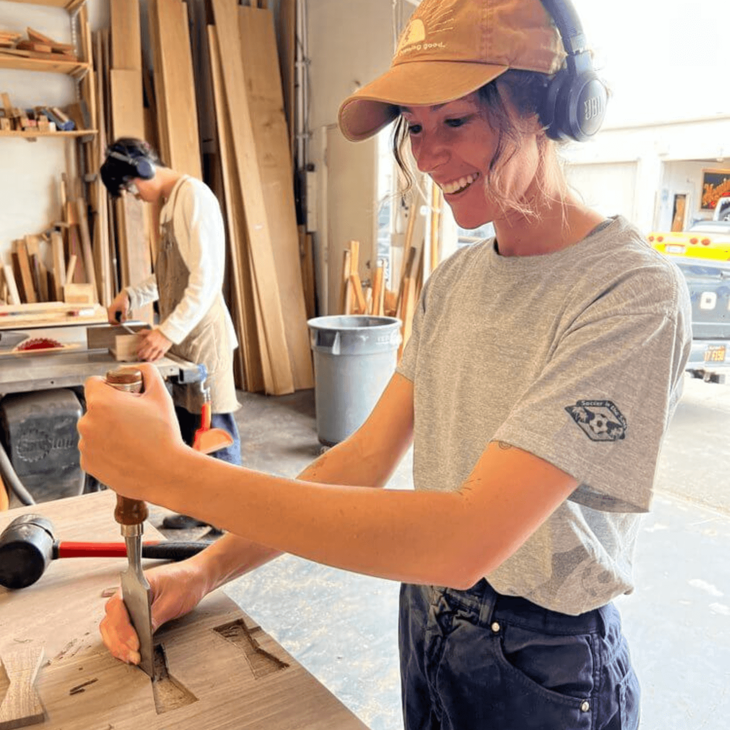 Woodworker chiseling wood in workshop with teamwork